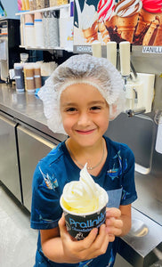 Enfant qui montre le joli sundae qu'il a fabriqué dans un atelier de crème glacée