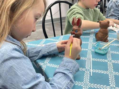 Enfant qui décore son chocolat dans un atelier de fabrication de chocolat de Pâques